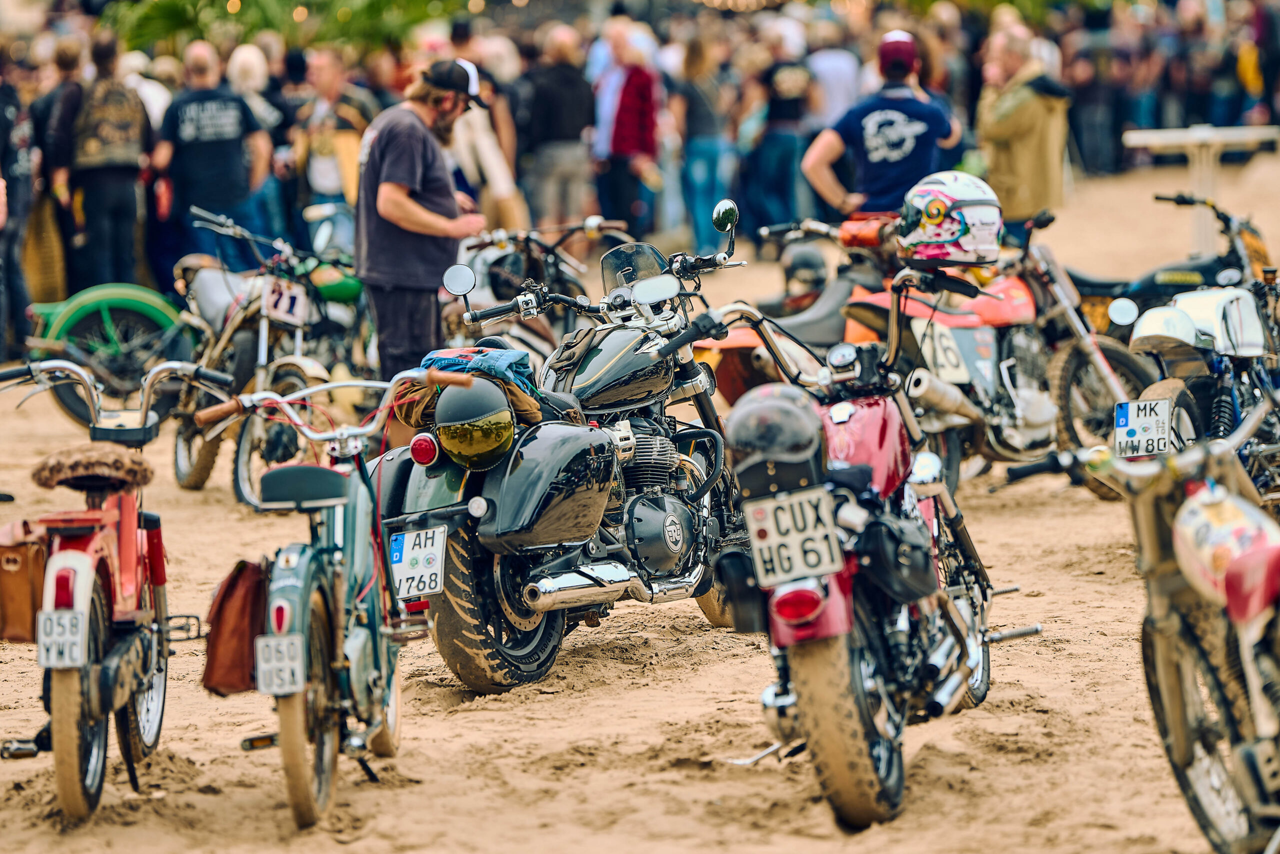 Vintage motorcycles and mopeds parked in the sand in front of the crowd at Wheels and Wake, Nethen Beach