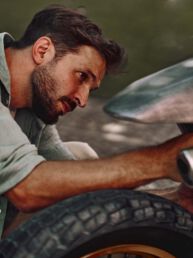 Builder Giovanni Mariani working on his raw aluminium Kawasaki KX250 at Deus Ex Machina in Milan