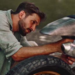Builder Giovanni Mariani working on his raw aluminium Kawasaki KX250 at Deus Ex Machina in Milan